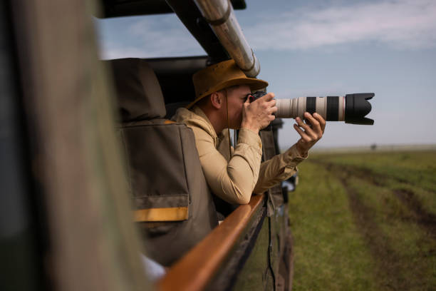 Expert photographer capturing animals on a Tanzania safari with his mirrorless camera Expert photographer capturing animals on a Tanzania safari with his mirrorless camera